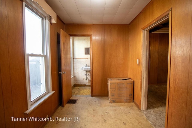 corridor featuring visible vents, wooden walls, and a healthy amount of sunlight