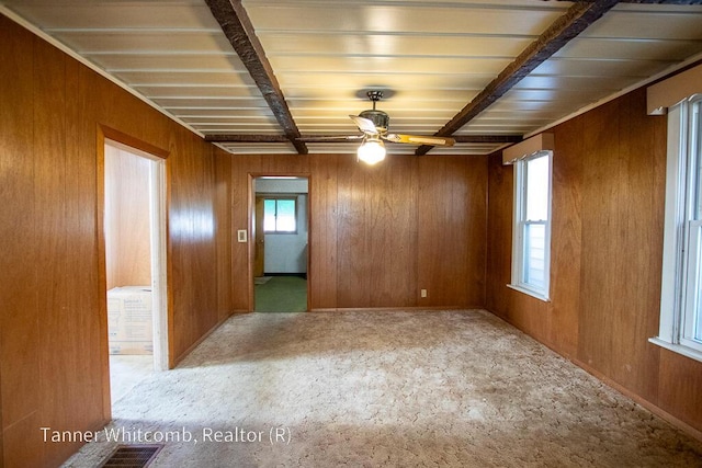 unfurnished room with beamed ceiling, wooden walls, and a ceiling fan