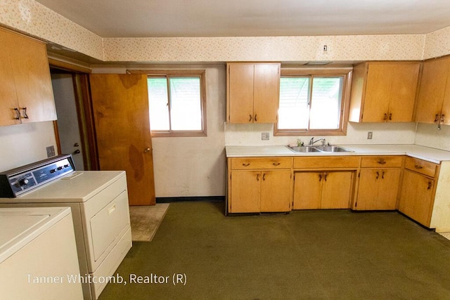 kitchen featuring a wealth of natural light, a sink, washer and dryer, wallpapered walls, and light countertops