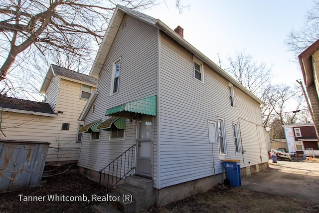 rear view of property with a chimney and entry steps