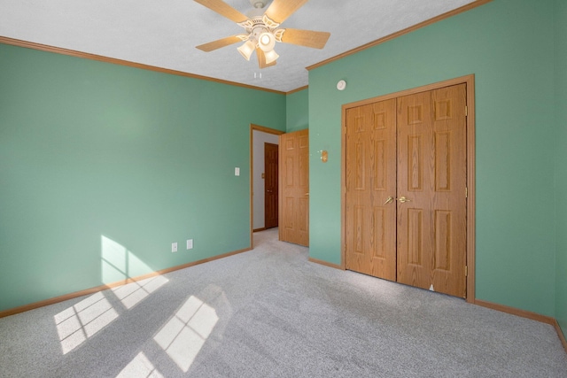 unfurnished bedroom featuring baseboards, carpet floors, ceiling fan, ornamental molding, and a closet