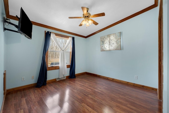 empty room with ceiling fan, wood finished floors, baseboards, and ornamental molding