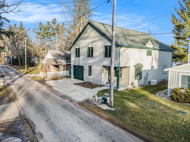 view of front of house with central AC unit, concrete driveway, and a front yard