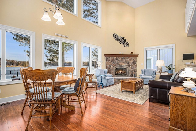 dining area with hardwood / wood-style floors, visible vents, baseboards, a fireplace, and a chandelier