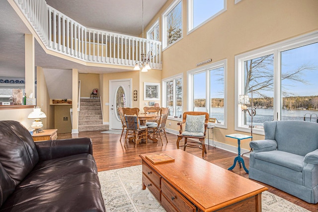 living room featuring baseboards, wood finished floors, stairs, and a water view