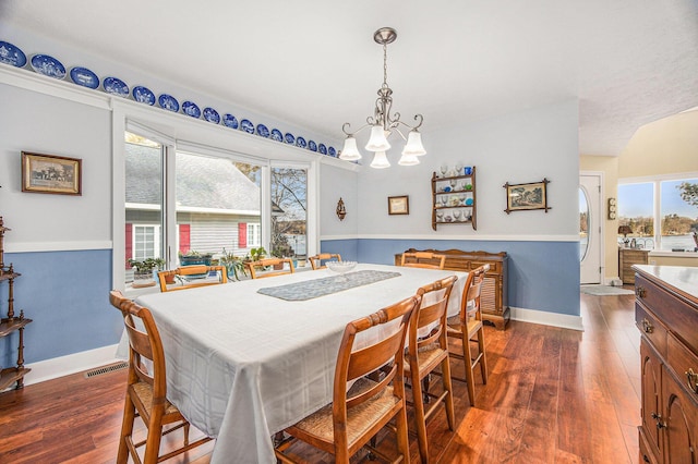 dining room featuring dark wood finished floors, visible vents, a chandelier, and baseboards