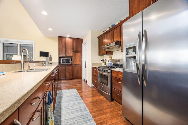 kitchen with dark wood-type flooring, a sink, under cabinet range hood, stainless steel appliances, and light countertops