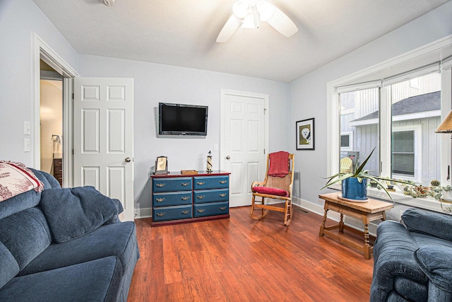 living area featuring baseboards, dark wood-type flooring, and ceiling fan