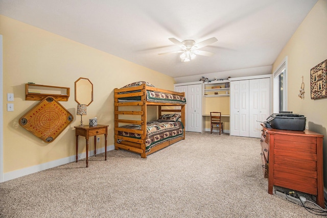 carpeted bedroom with baseboards, multiple closets, and ceiling fan