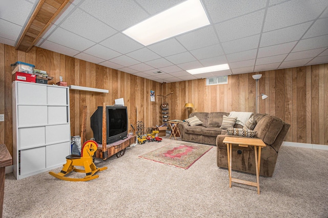 living area featuring visible vents, wood walls, a paneled ceiling, and carpet