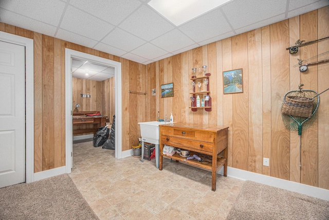 interior space featuring wooden walls, a paneled ceiling, and baseboards