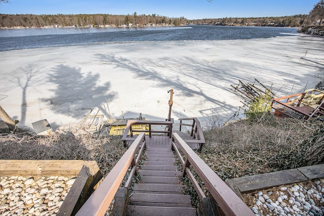 dock area with a water view, a view of trees, and stairs