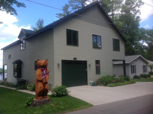 view of front facade featuring central air condition unit, an attached garage, and driveway