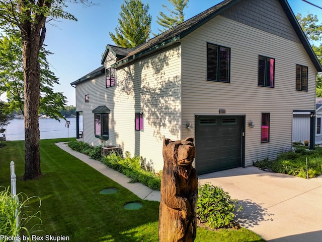 5569 Front St, Newaygo, MI 49337 - view of front facade featuring a water view, a front lawn, a garage, and driveway