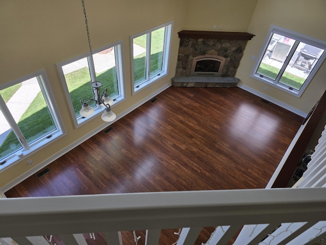 5569 Front St, Newaygo, MI 49337 - unfurnished living room featuring dark wood finished floors, a stone fireplace, and a towering ceiling