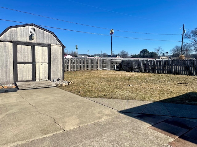 view of yard with an outdoor structure, a fenced backyard, a storage shed, and a patio area