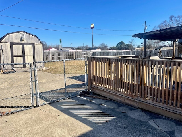 view of gate featuring an outdoor structure, a storage shed, and a fenced backyard