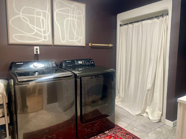 laundry room featuring washing machine and clothes dryer, cabinet space, marble finish floor, and baseboards