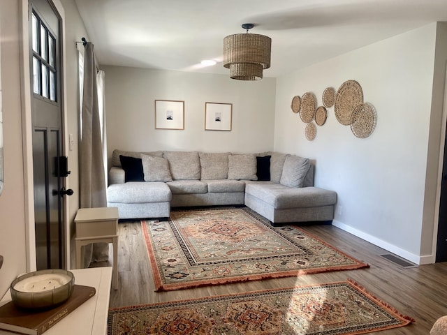 living area with visible vents, baseboards, and wood finished floors