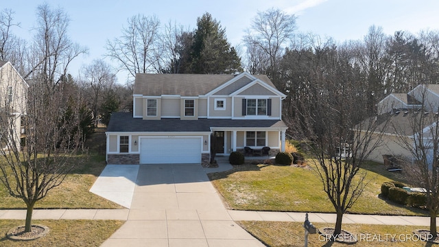 traditional-style home with a front yard, concrete driveway, covered porch, and stone siding