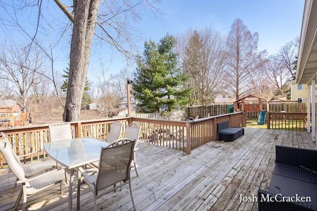 deck featuring a fenced backyard, outdoor dining space, and a playground