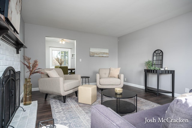 living room featuring ceiling fan, baseboards, wood finished floors, and a fireplace