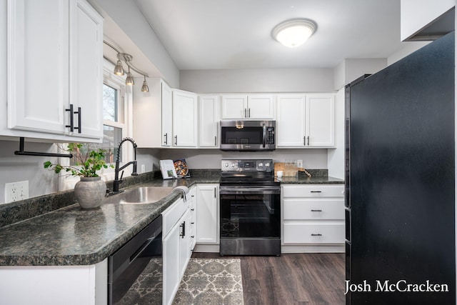 kitchen featuring dark countertops, white cabinetry, stainless steel appliances, and a sink