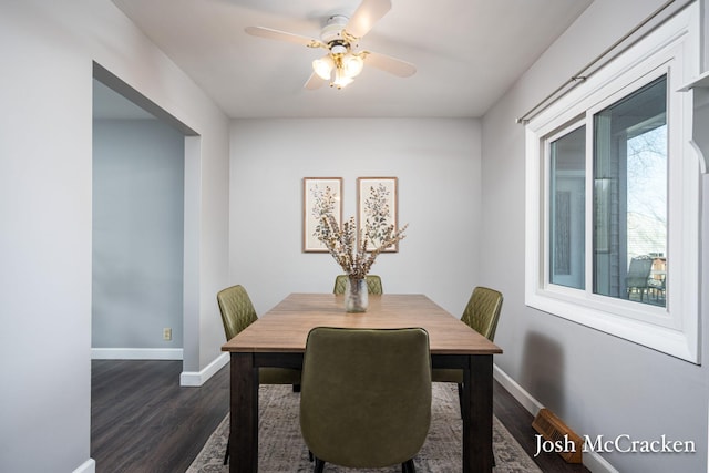 dining room with dark wood finished floors, a ceiling fan, and baseboards