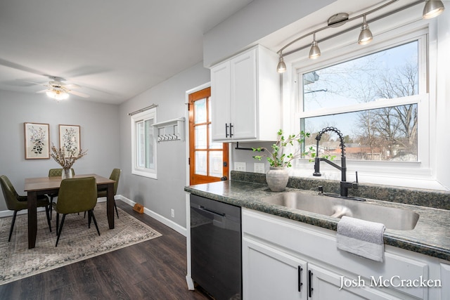 kitchen with dishwashing machine, plenty of natural light, dark countertops, and a sink