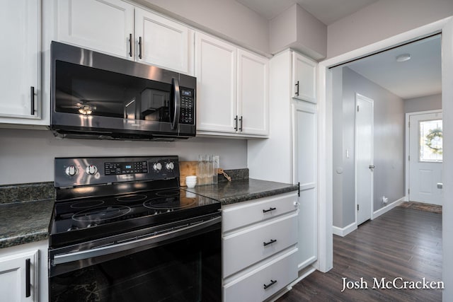 kitchen with black range with electric stovetop, dark countertops, dark wood finished floors, white cabinets, and baseboards