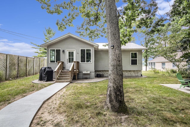 view of front of house featuring a front yard, fence, and metal roof