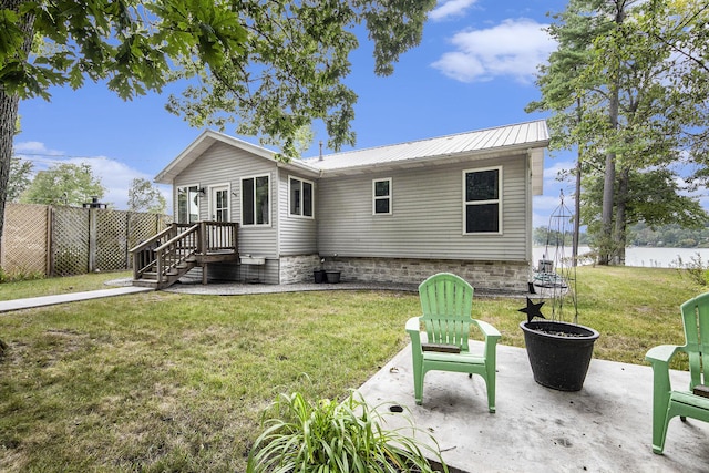 rear view of property with metal roof, a patio, a lawn, and fence