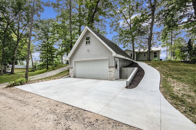 view of property exterior with concrete driveway, a yard, and stone siding