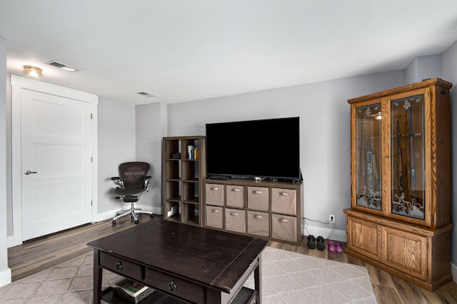 living room with visible vents, baseboards, and wood finished floors