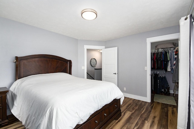 bedroom featuring a spacious closet, a closet, baseboards, and dark wood-style flooring