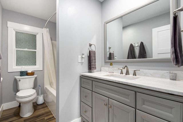 bathroom with toilet, shower / bath combo, wood finished floors, baseboards, and vanity