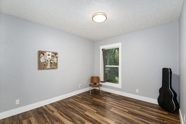 spare room with dark wood finished floors, a textured ceiling, and baseboards