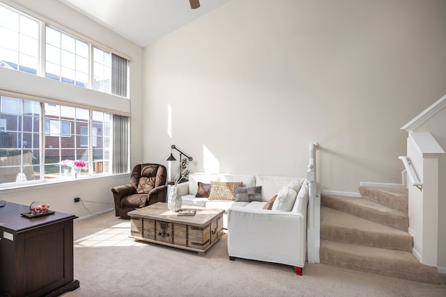 carpeted living room with stairway, ceiling fan, high vaulted ceiling, and baseboards