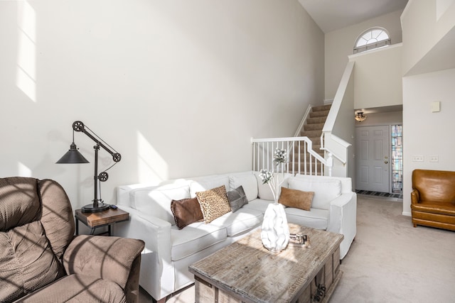 living area featuring light carpet, stairway, and a high ceiling