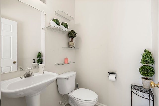 bathroom featuring toilet, baseboards, and a sink