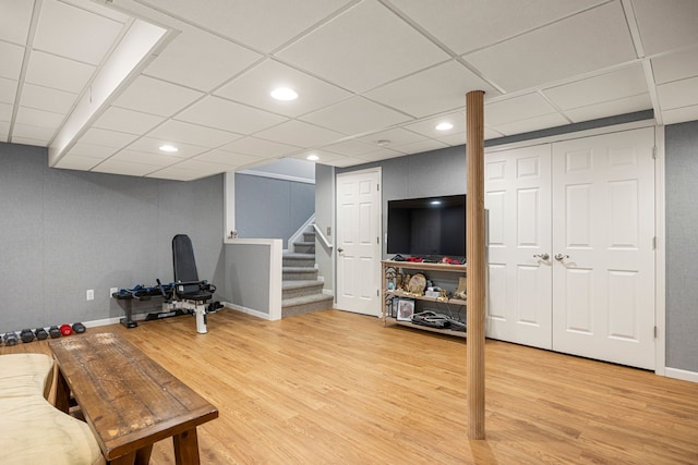 exercise room with recessed lighting, baseboards, a paneled ceiling, and light wood-style floors