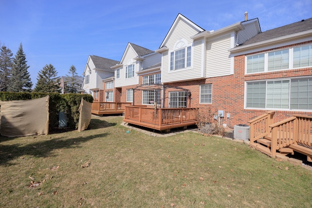 back of house with brick siding, central air condition unit, a lawn, and a wooden deck