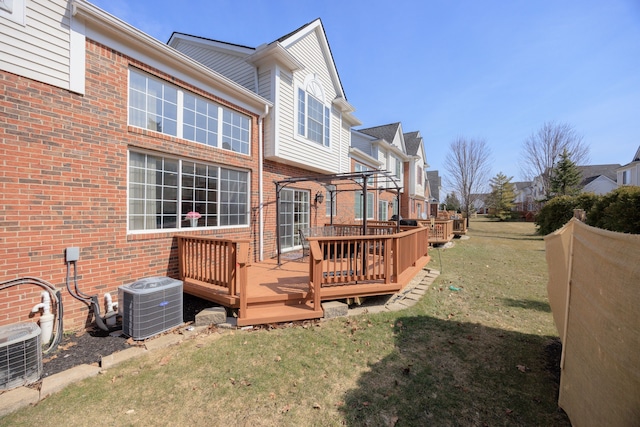 back of property featuring a lawn, a deck, a residential view, brick siding, and central AC unit