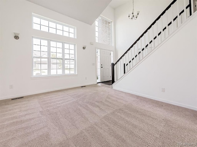 foyer entrance with baseboards, visible vents, stairs, a towering ceiling, and carpet flooring