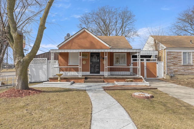 bungalow-style house featuring brick siding, a front lawn, fence, and covered porch