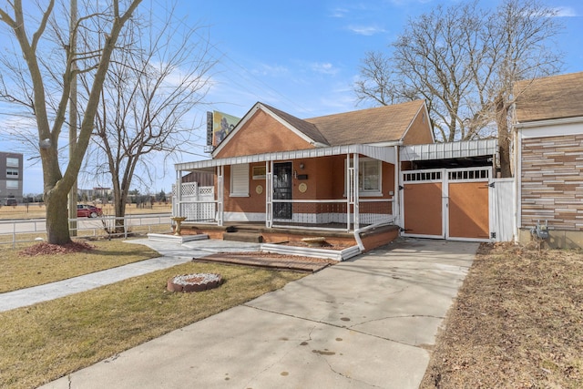 view of front of house with a porch, concrete driveway, roof with shingles, and fence