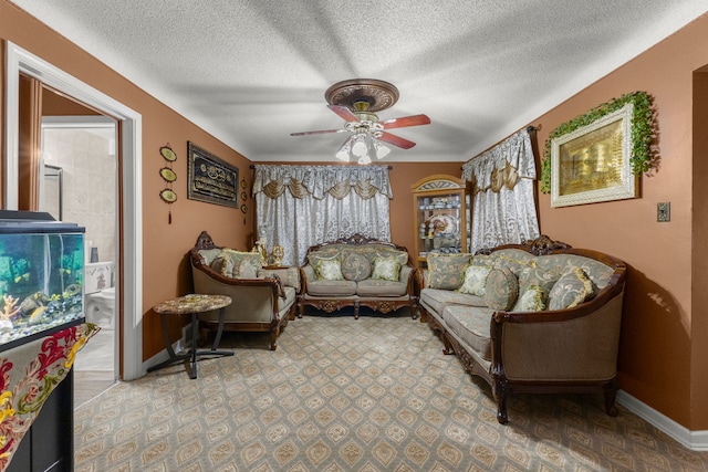 living area with a ceiling fan, baseboards, and a textured ceiling