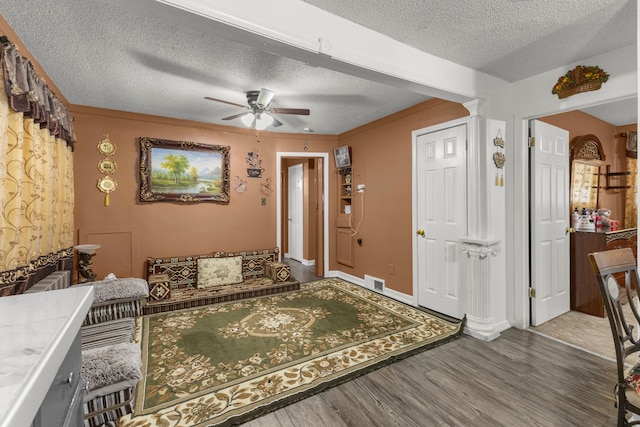 entryway with visible vents, ceiling fan, wood finished floors, a textured ceiling, and ornate columns