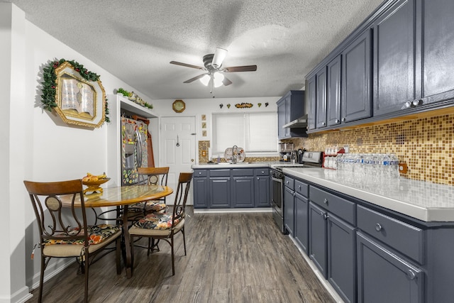 kitchen with a sink, dark wood-type flooring, backsplash, and electric stove