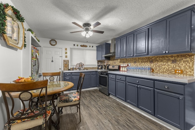 kitchen with dark wood-style flooring, a sink, stainless steel range oven, wall chimney range hood, and tasteful backsplash